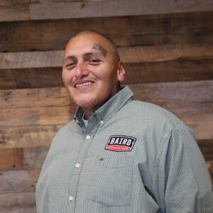 Headshot of foreman, Javier Gonzalez, taken at the San Antonio office. He is smiling and wearing a green checkered Baird button down shirt.