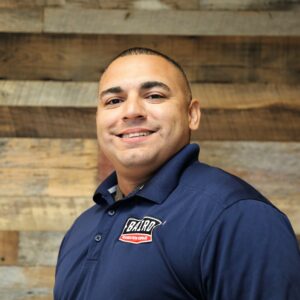 Headshot of foreman, Josh Sanchez, taken at the San Antonio office. He is smiling and wearing a navy Baird polo shirt.