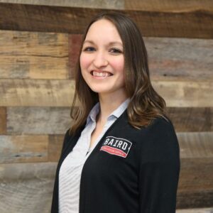 Headshot of customer care specialist, Soleil Olvera, taken at the San Antonio office. She is smiling and wearing a black Baird cardigan.