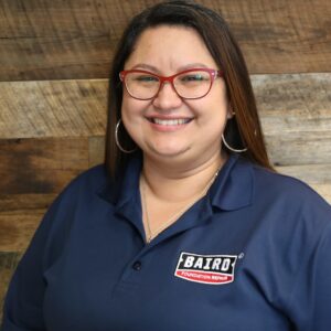 Headshot of Customer Care Representative Charline Millice, taken at the San Antonio office. She is smiling and wearing a navy Baird polo shirt.