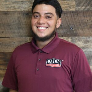 Headshot of co-foreman, William Martinez, taken at the San Antonio office. He is smiling and wearing a maroon Baird polo shirt.