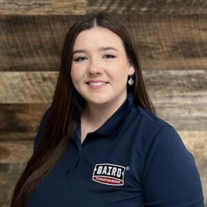 Headshot of our marketing assistant, Kara Fisher, taken in the Corpus Christi office. She is smiling and wearing a black Baird Foundation Repair polo shirt.
