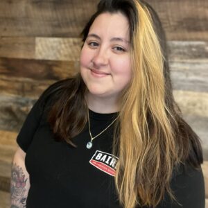Cropped headshot of customer care specialist, Jenn Young, taken at the San Antonio office. She is smiling and wearing a black Baird Foundation Repair t-shirt.