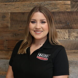 Headshot of marketing manager, Shelby Barker, taken at the San Antonio office. She is smiling and wearing a black Baird Foundation Repair polo shirt.