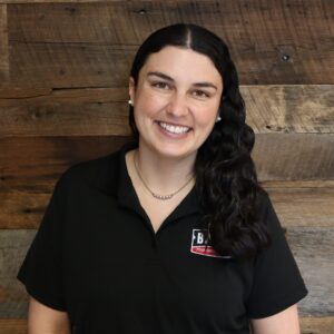 Headshot of system design specialist, Brittney Laurel, taken in the Corpus Christi office. She is smiling and wearing a black Baird polo shirt.