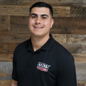 Headshot of system design specialist, Jacob Keaton, taken at the San Antonio office. He is smiling and wearing a black Baird Foundation Repair polo shirt.