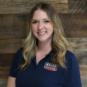 Headshot of system design specialist, Kamron Poppell, taken at the Houston office. She is smiling and wearing a black Baird polo shirt.
