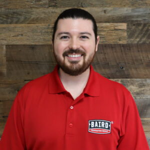 Headshot of the system design specialist, Alfonso Guajardo, taken at the San Antonio office. He is smiling and wearing a red Baird polo shirt.