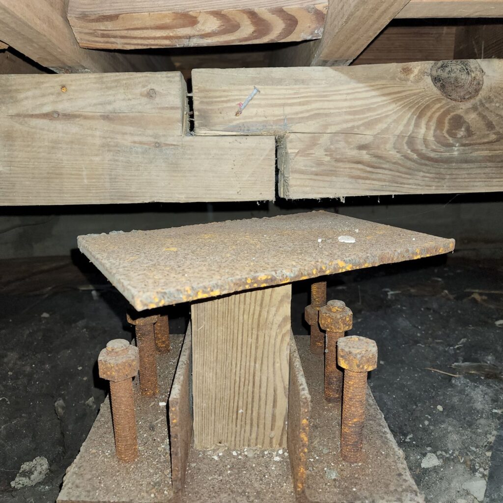 Close up of a gap between a home's wooden pier and beam foundation in a crawlspace.