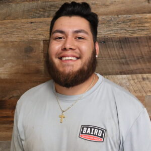 Headshot of installer, Jordan Valdez, taken at the San Antonio office. He is smiling and wearing a light gray Baird Foundation Repair t-shirt.