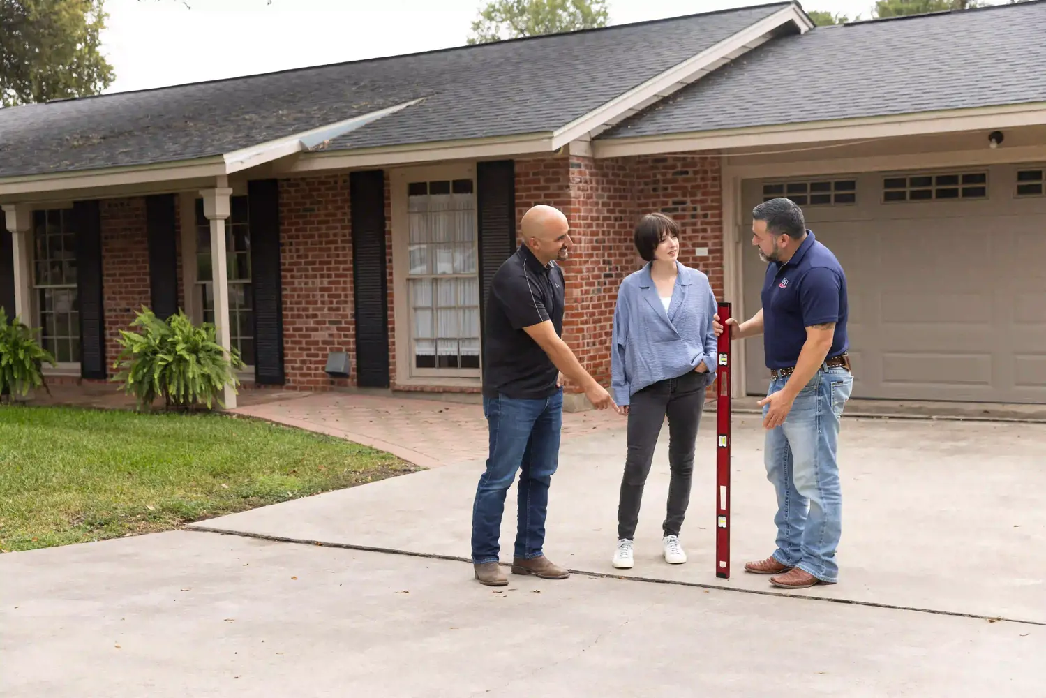 Homeowners outside on driveway during concrete repair inspection.