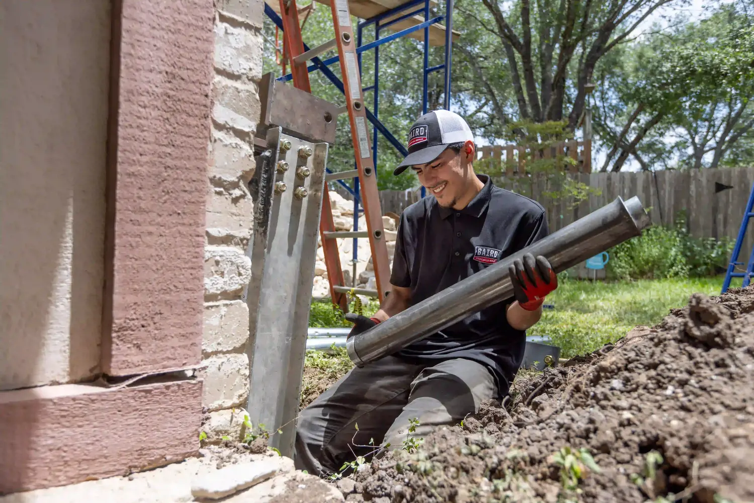 Baird-Trip-182 (1) Production team member installing push pier materials at footing of home.