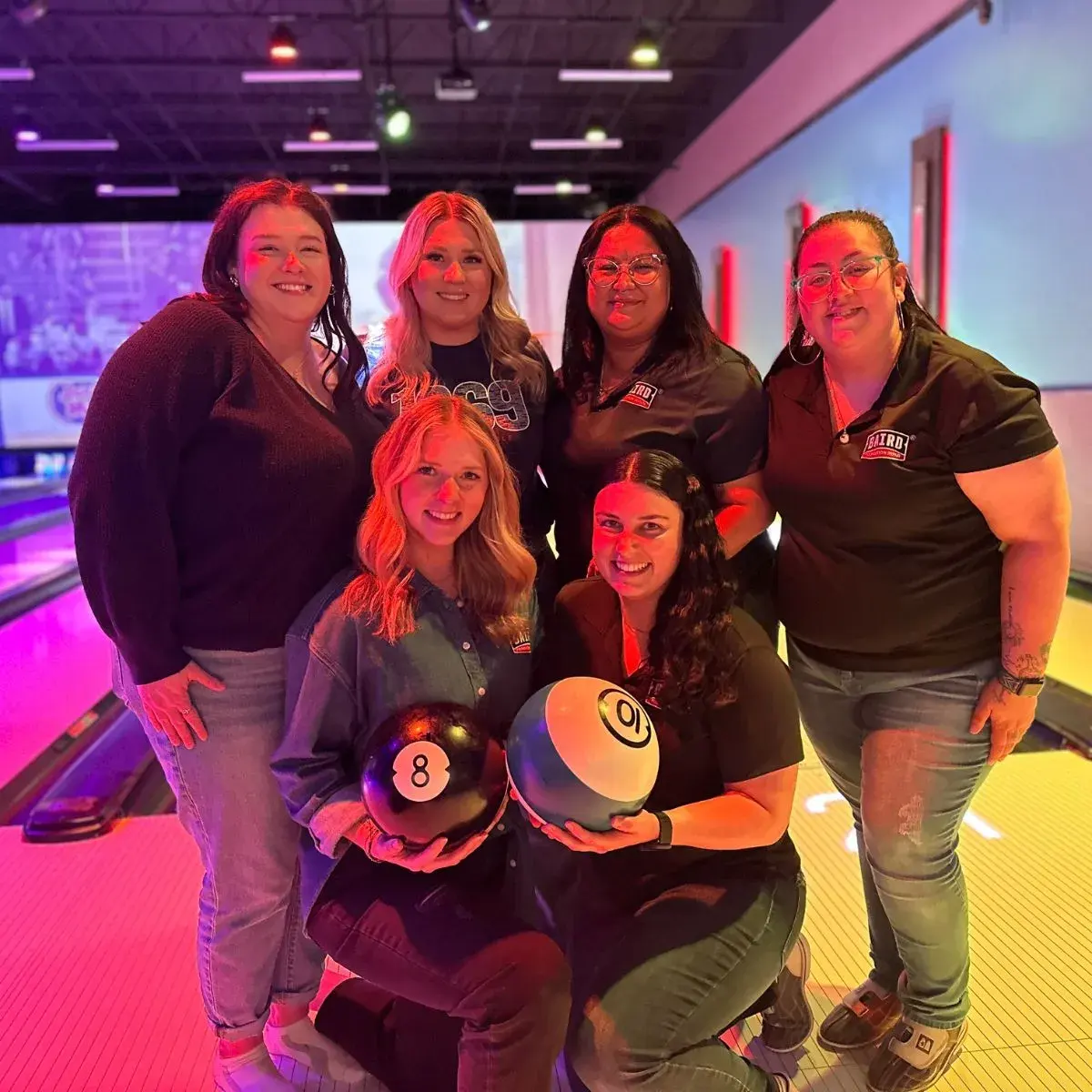 Marketing and customer care team members smile at bowling alley