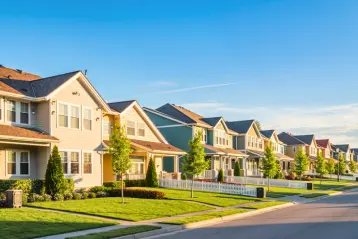 A row of well-maintained two-story suburban homes with green lawns and landscaping on a sunny day in a Texas neighborhood.
