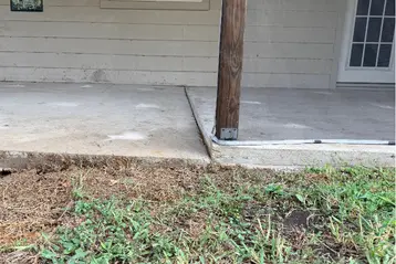 Sunken concrete porch slab with visible gap and uneven edge next to a wooden support post at a residential home