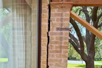 Before photo showing a brick support column with a large vertical crack