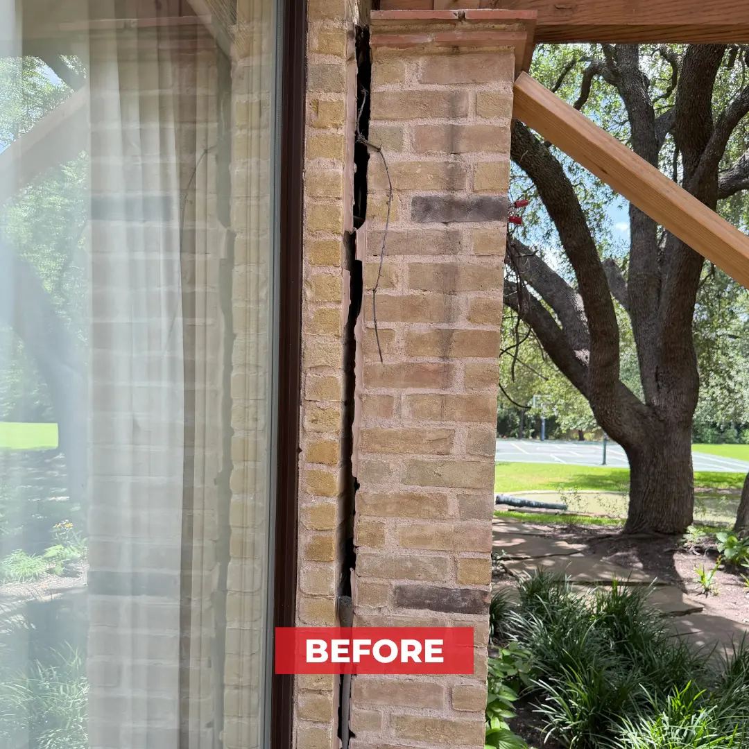 Vertical crack in a brick support column on a home's exterior, near a window and covered patio.
